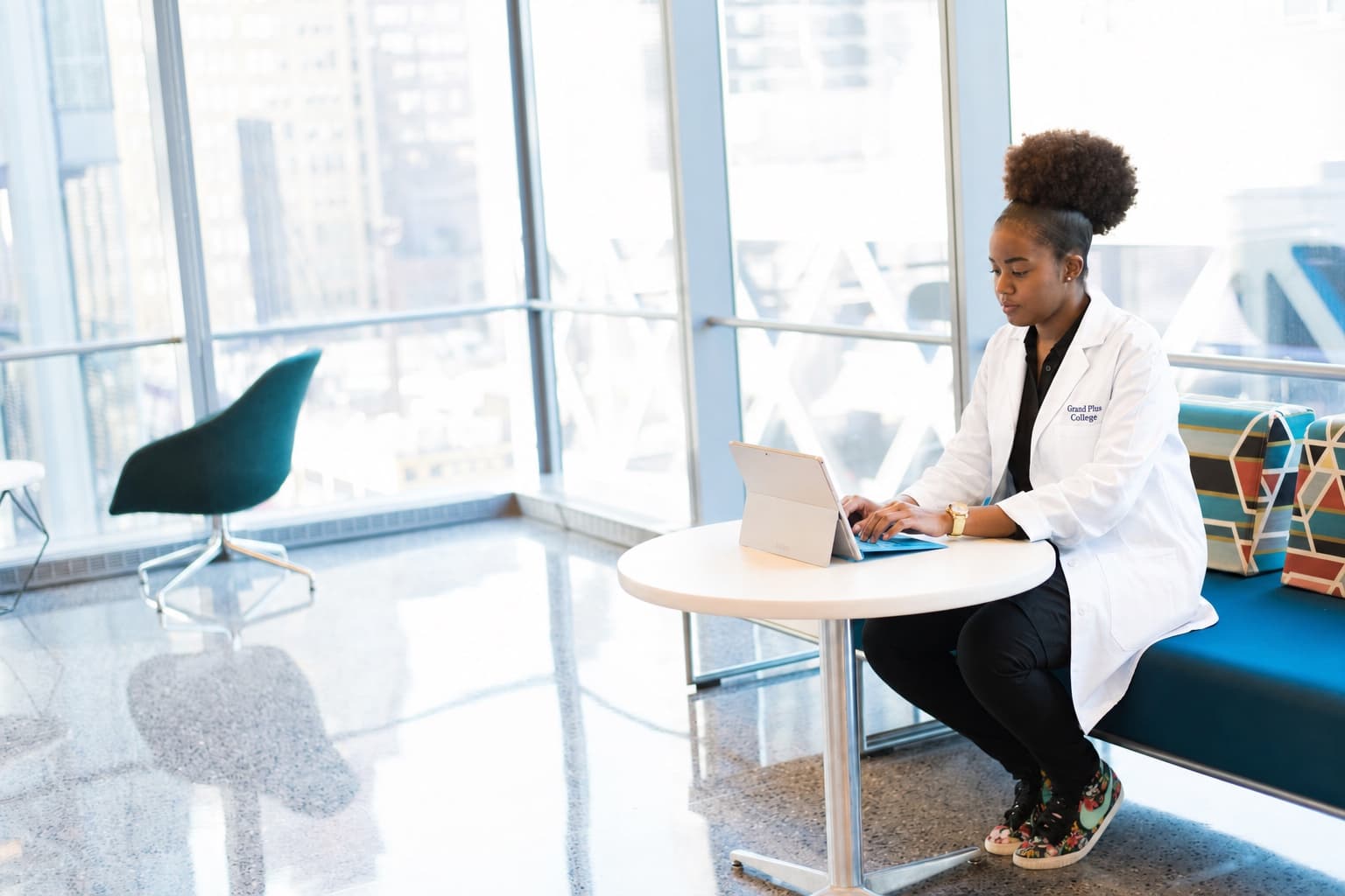 Student in a Grandplus College lab coat working at a laptop